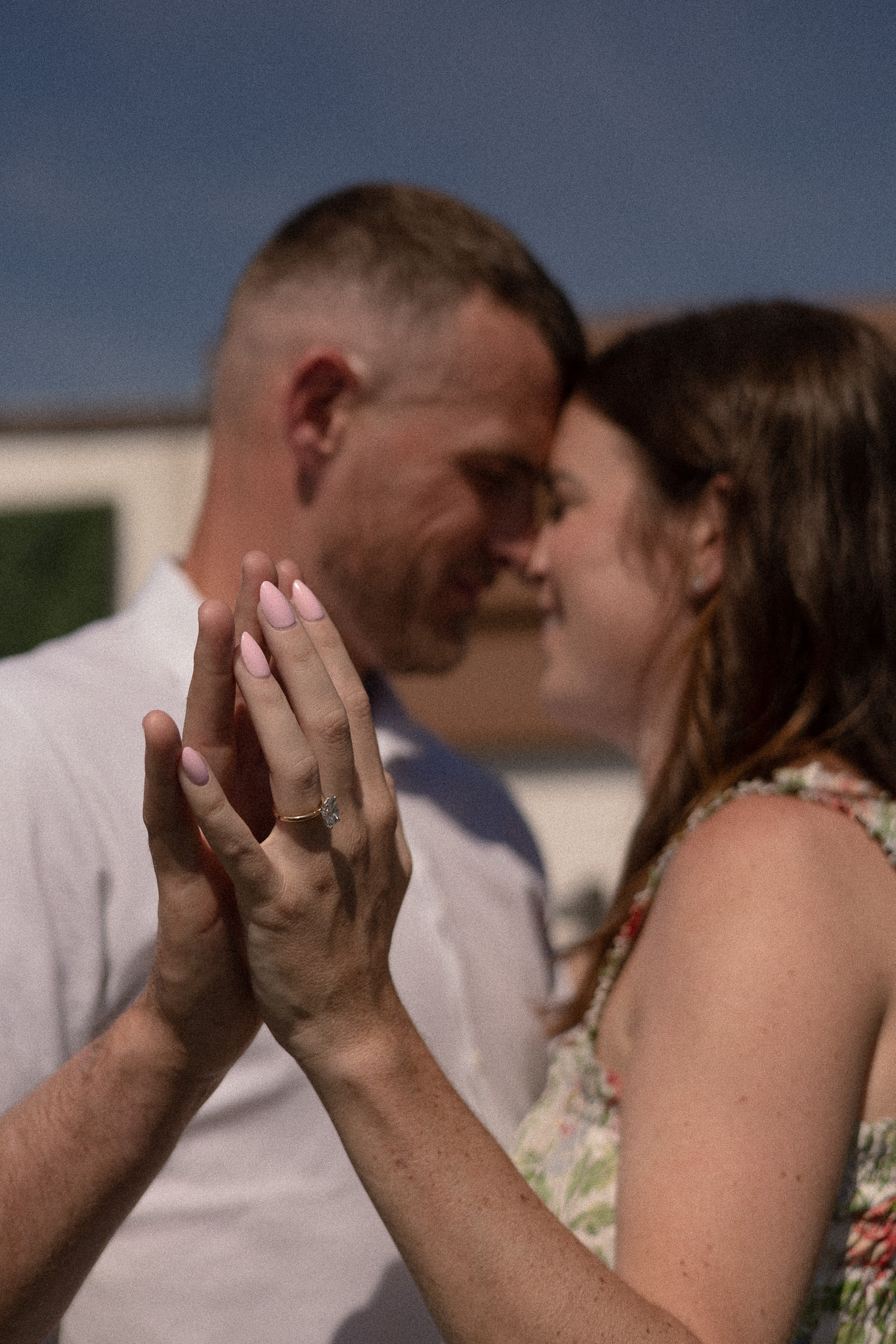 Couple in a soft embrace on a Florida Gulf beach at golden hour, smiling at each other against the open horizon.