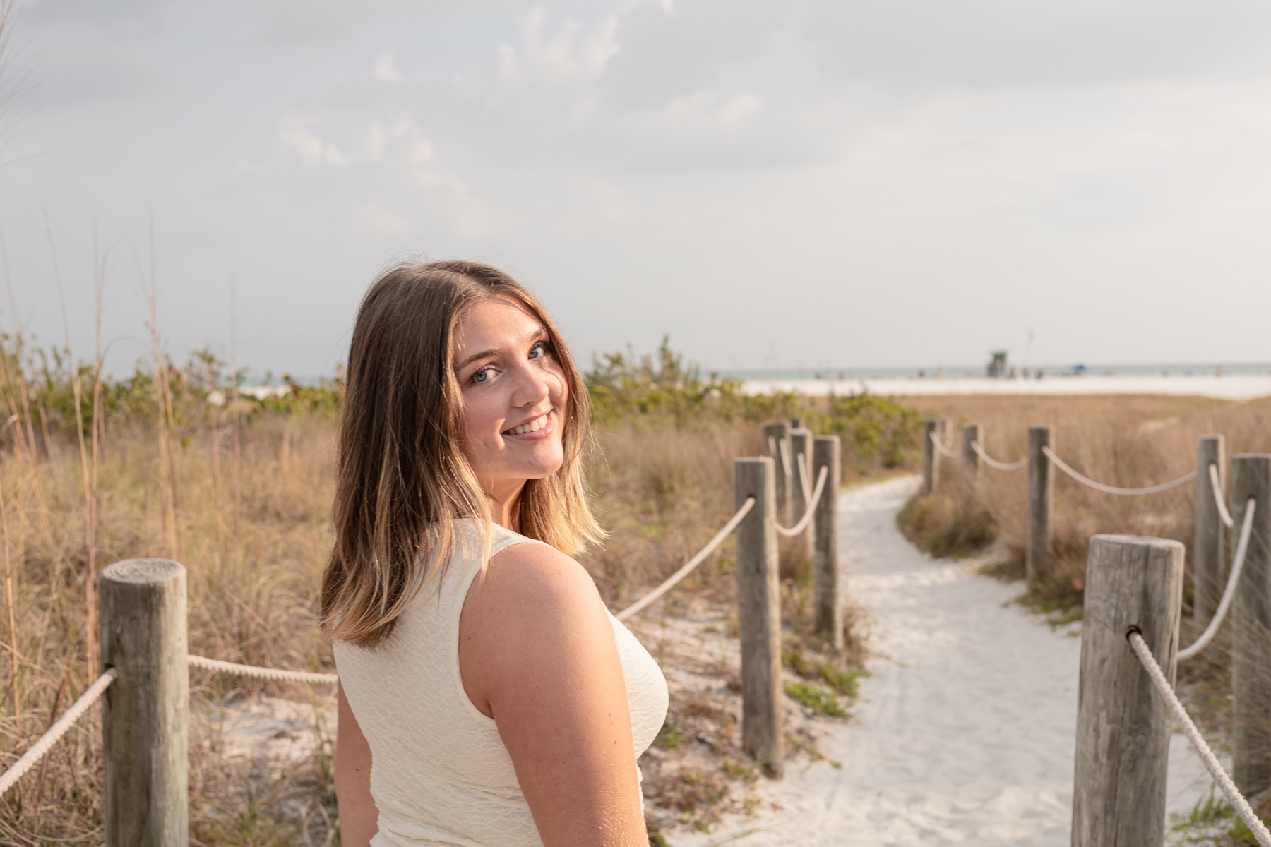 Over-the-shoulder smile on the sandy boardwalk