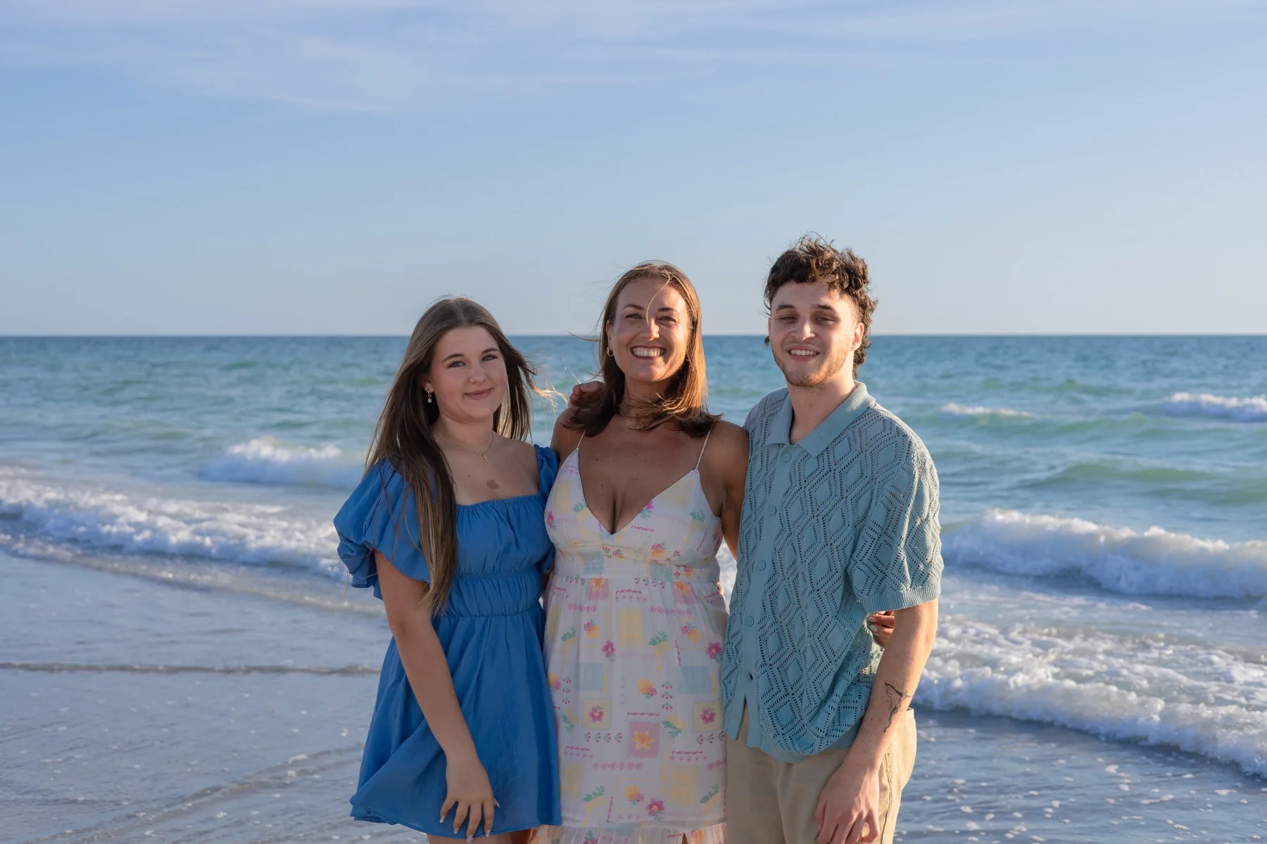 Mother and her two children arm-in-arm at the water's edge.