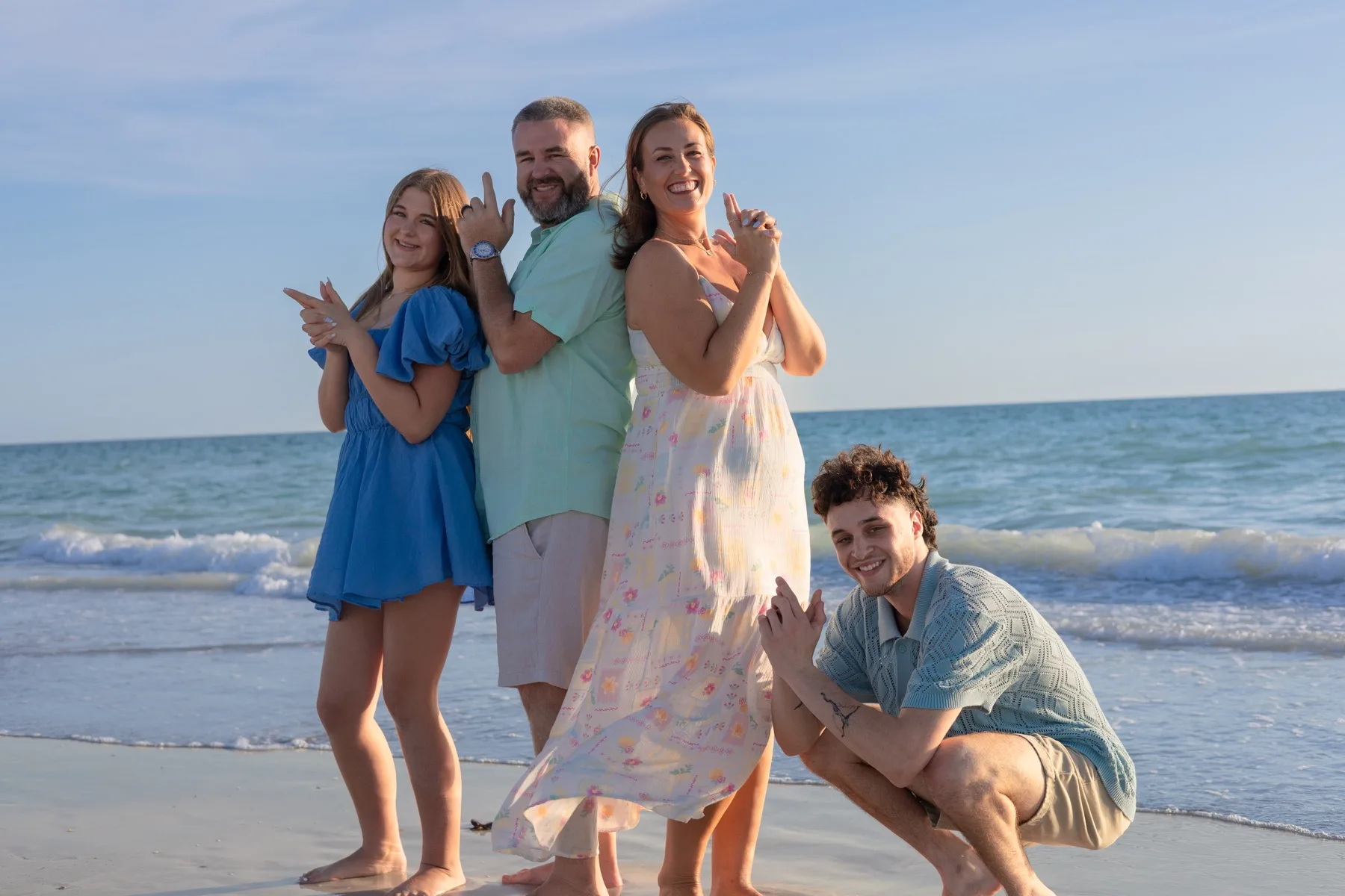 Family of four walking together on warm sand at sunset on a St. Petersburg beach.