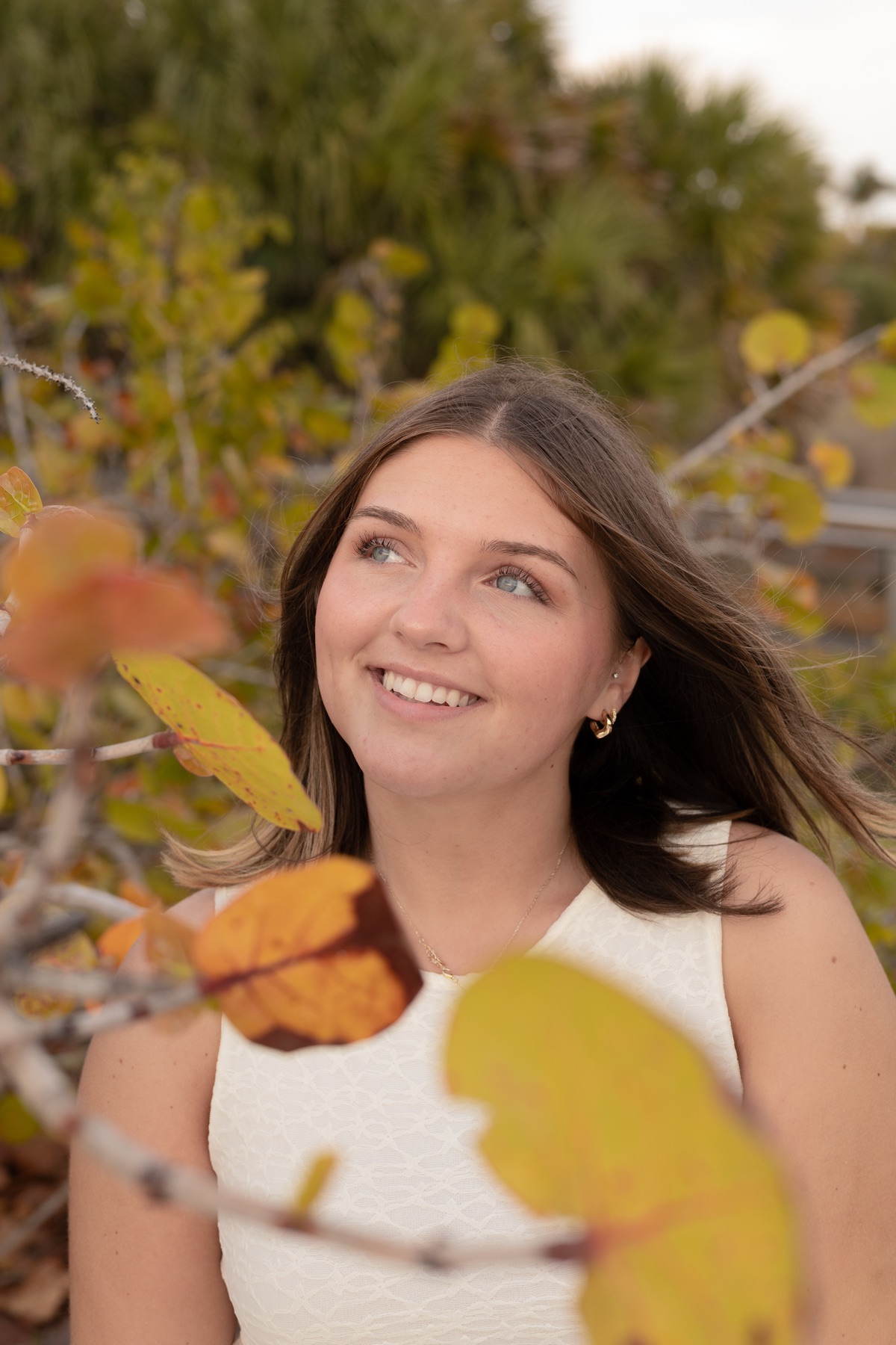 Smiling brightly amid autumn-toned sea-grape leaves